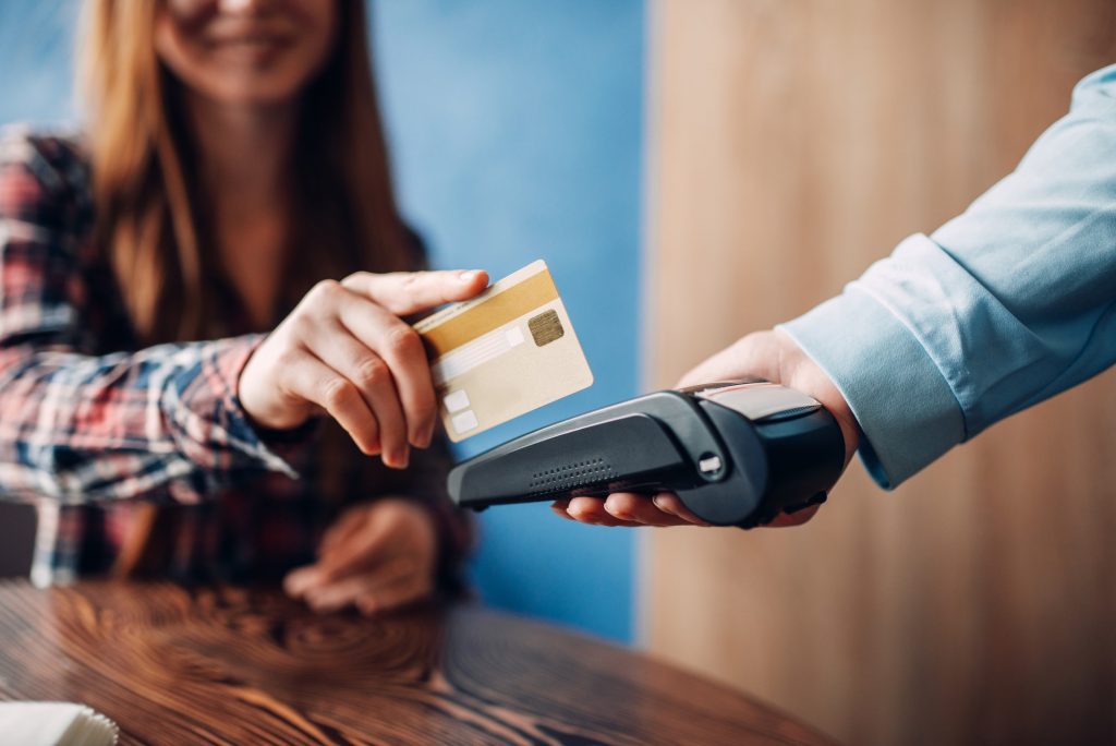 Young woman paying with credit card in cafe